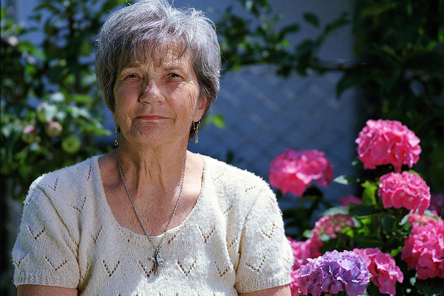 Elderly lady in the garden with flowers